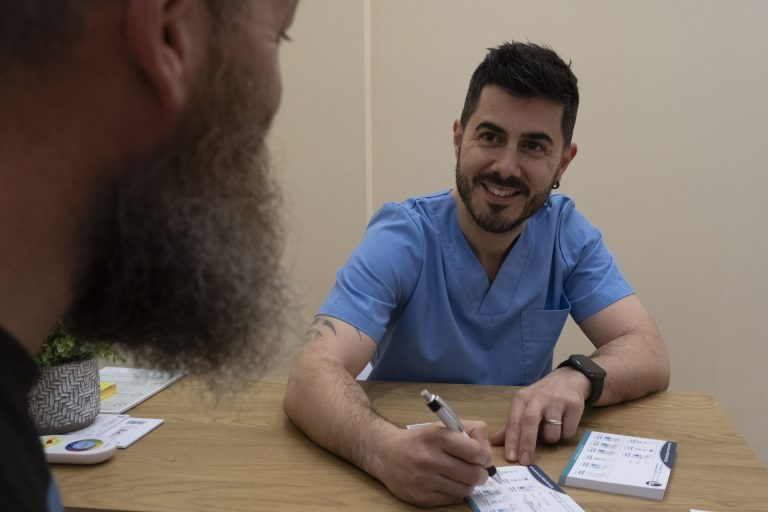 Enrique Salinas, podólogo, atendiendo a un paciente en la mesa de consulta de Clínica Lebén