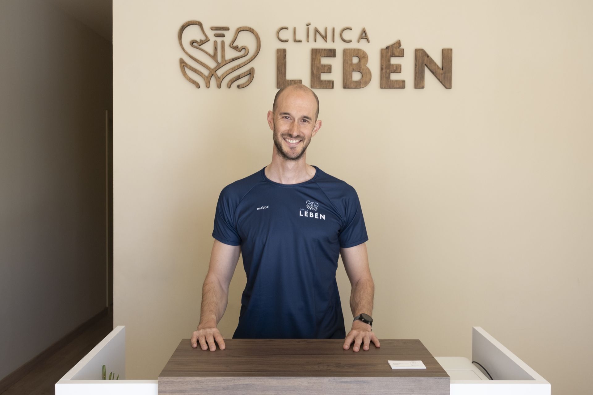 Recepción de Clínica Lebén en Paterna con el logotipo de madera y Miguel Górriz, nutricionista deportivo, tras el mostrador