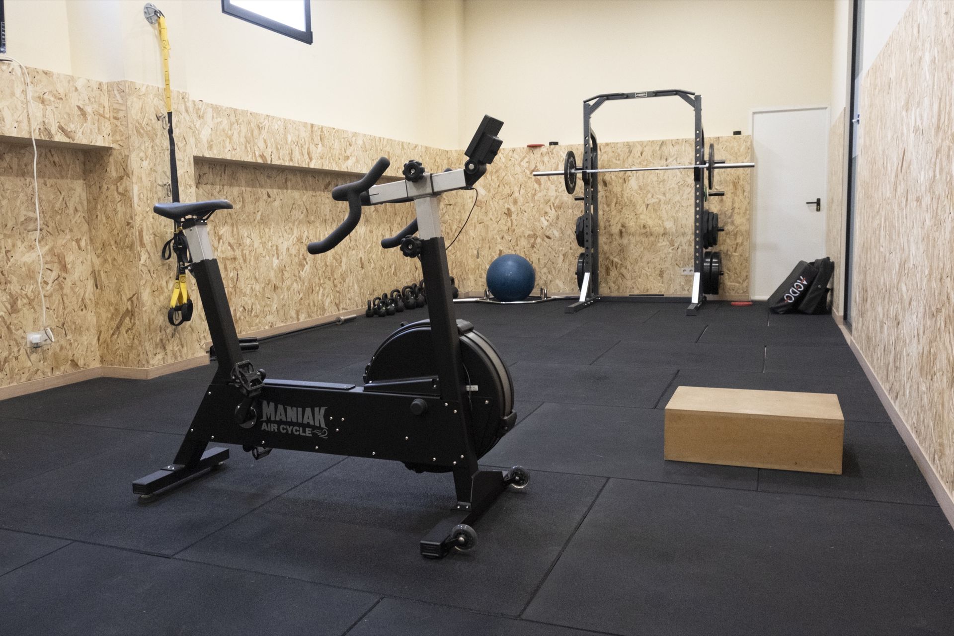 Sala de entrenamiento de Clínica Lebén con bicicleta de aire, rack de sentadillas, fitball y suelo de caucho