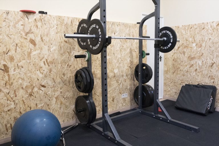Rack de sentadillas con barra y discos en la sala de entrenamiento de Clínica Lebén